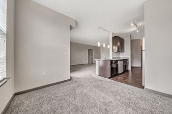 A spacious living room with a kitchen area in the background.